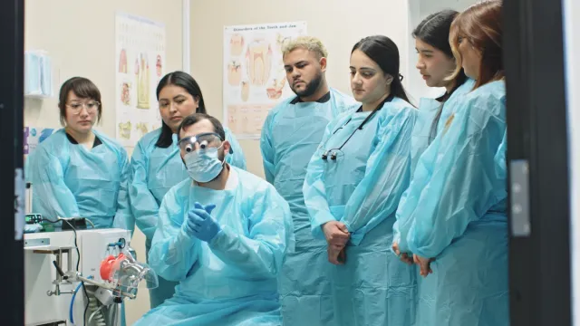 Group of students observing Dr. Kraishan perform a clinical demonstration.